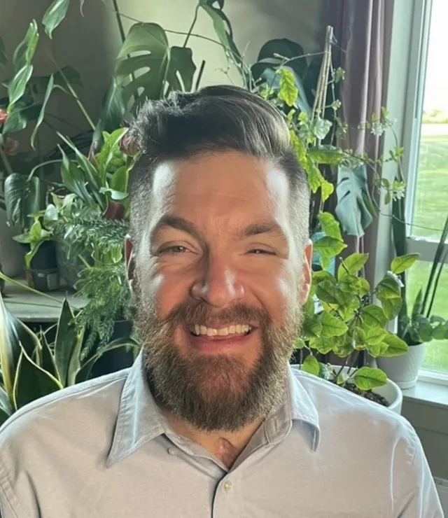 David Sussberg, founder of EarthDesign, smiling beside leafy plants